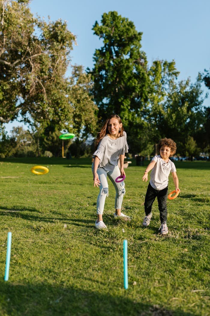 A joyful moment of a mother and son playing ring toss in a sunny park.